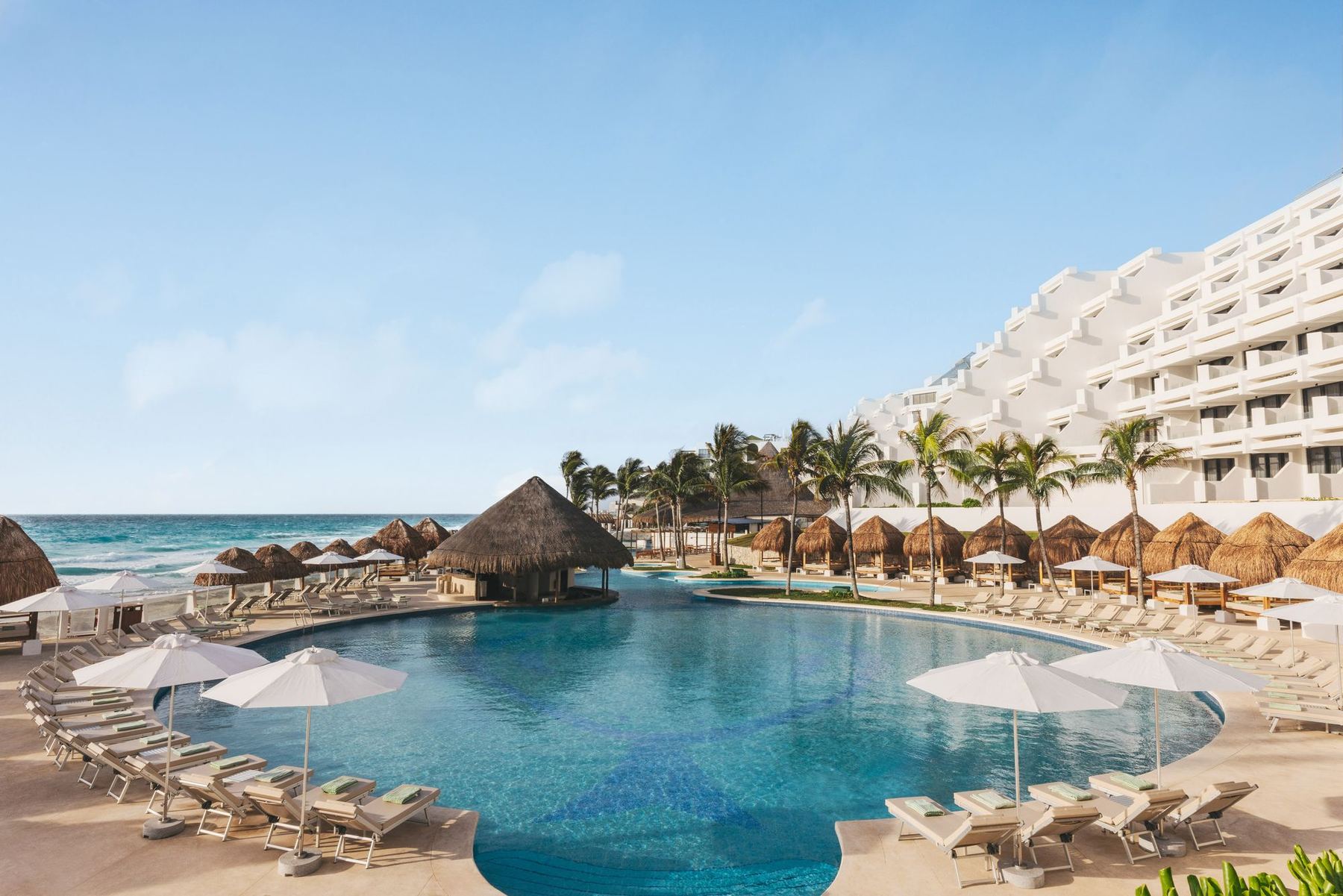 A wide resort pool with palapas at Paradisus Cancún