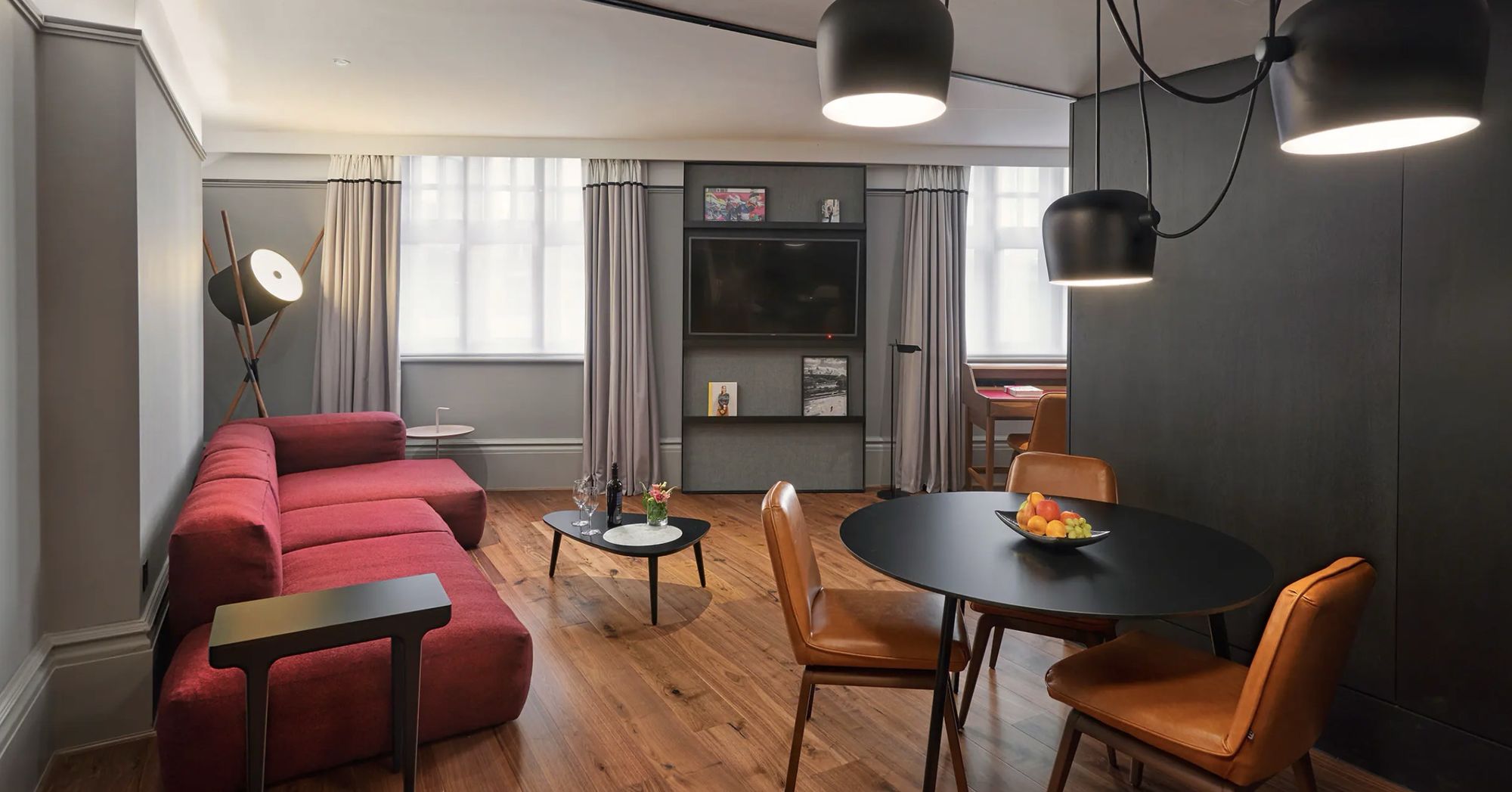 A suite with a red sofa and a round dining table