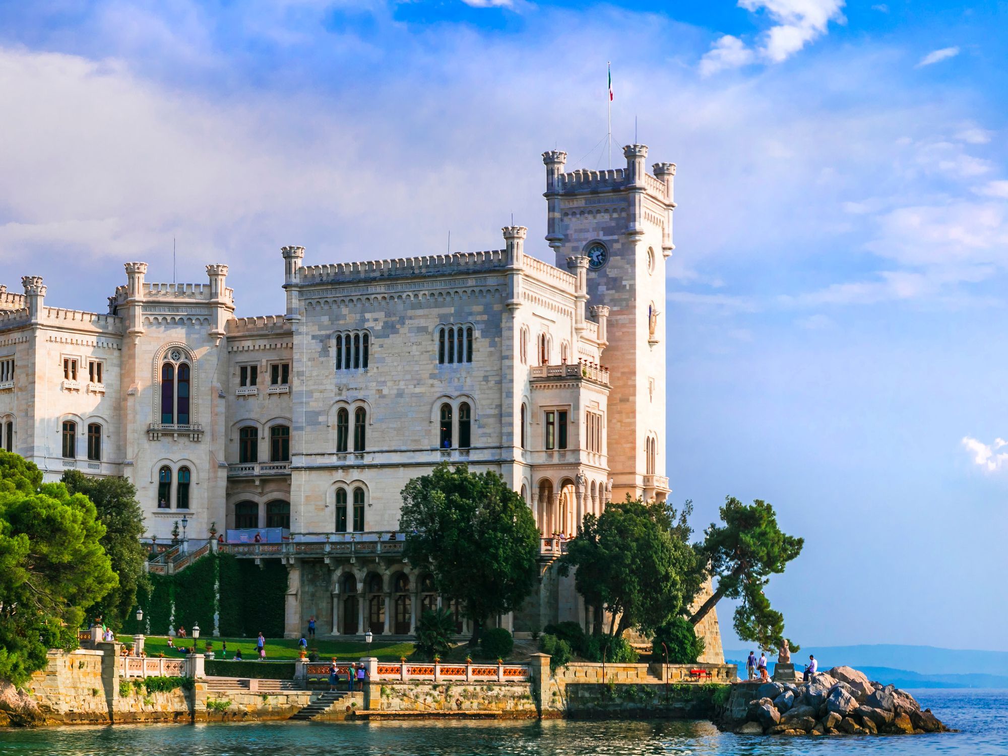 A white seaside castle on the Italian coast, framed by trees
