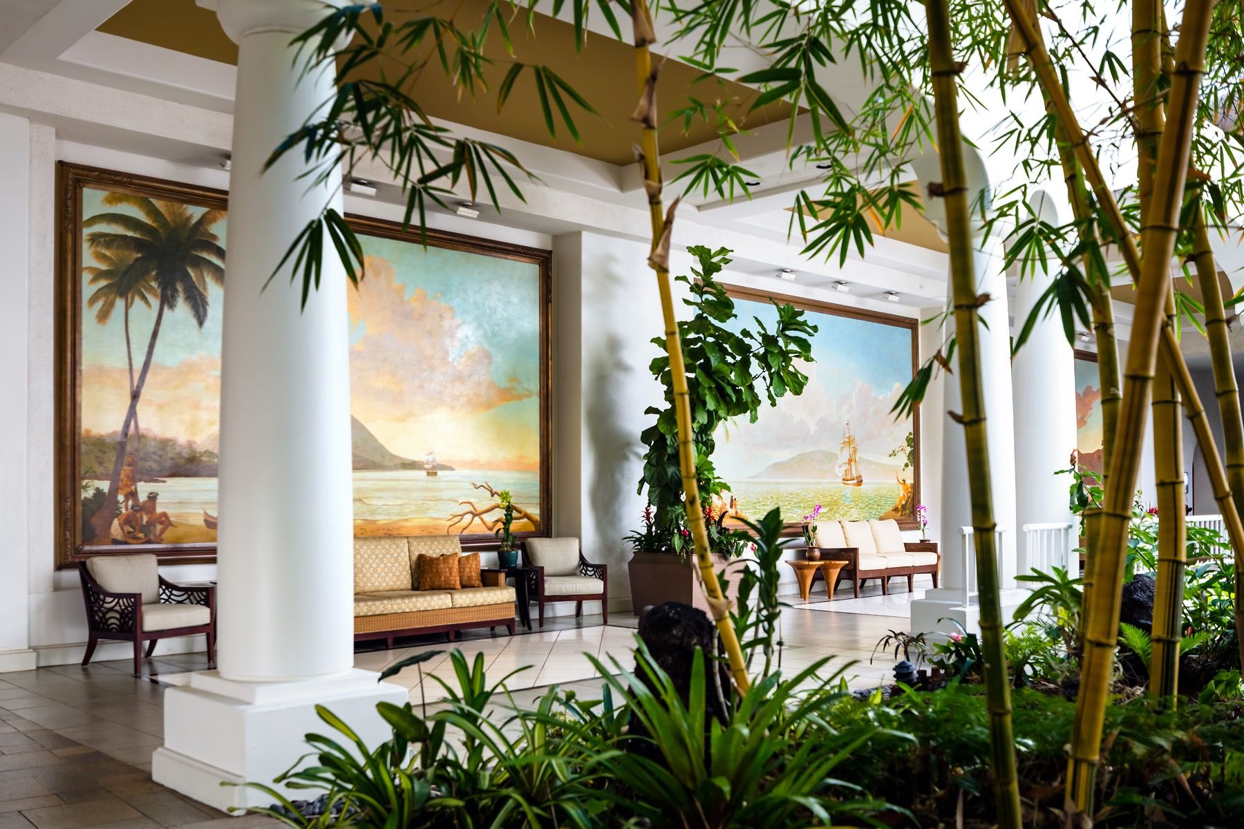The open-air lobby breezeway, with bamboo, white columns, and painted island murals