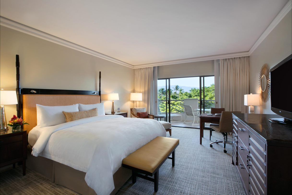 A guest room with a four-poster king bed and a lanai looking out to the sea