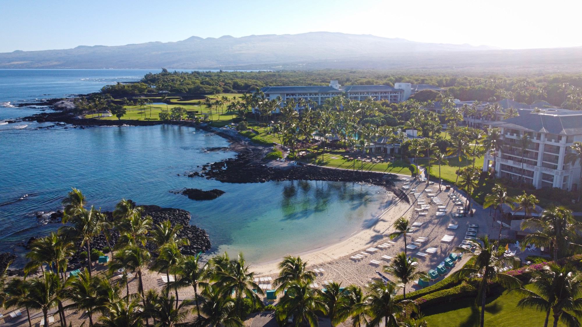 The sheltered cove of Pauoa Bay and the resort's lawns and palms, with the Kohala mountains beyond