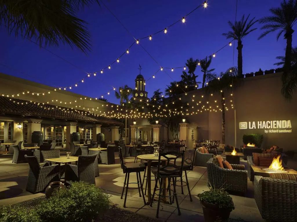 The courtyard of La Hacienda at night under string lights, with fire pits