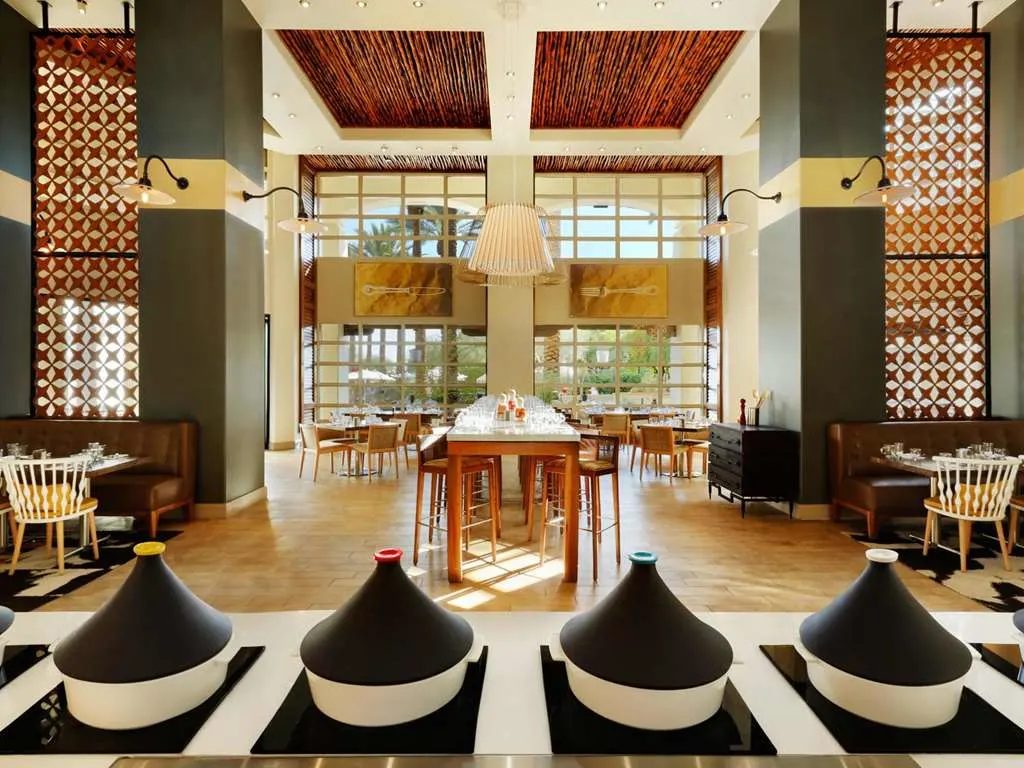 A bright restaurant with lattice screens and a long table of tagines
