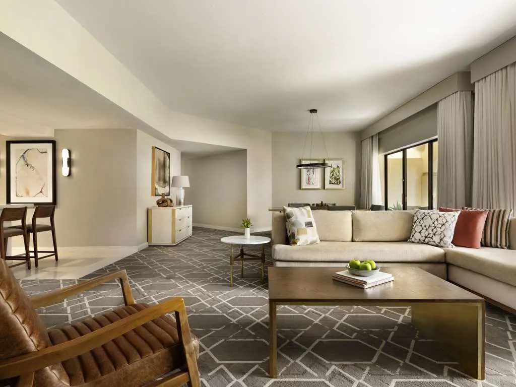 A suite lounge with a large sectional sofa and a geometric rug