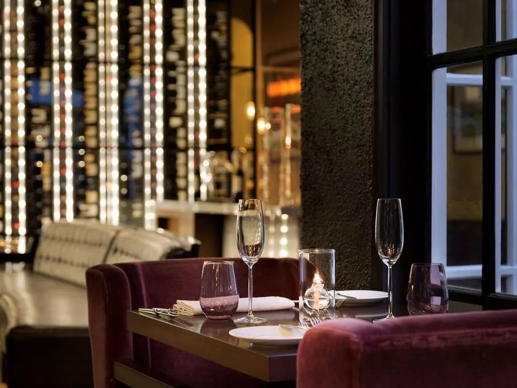 A candlelit table for two with a wall of wine glowing behind