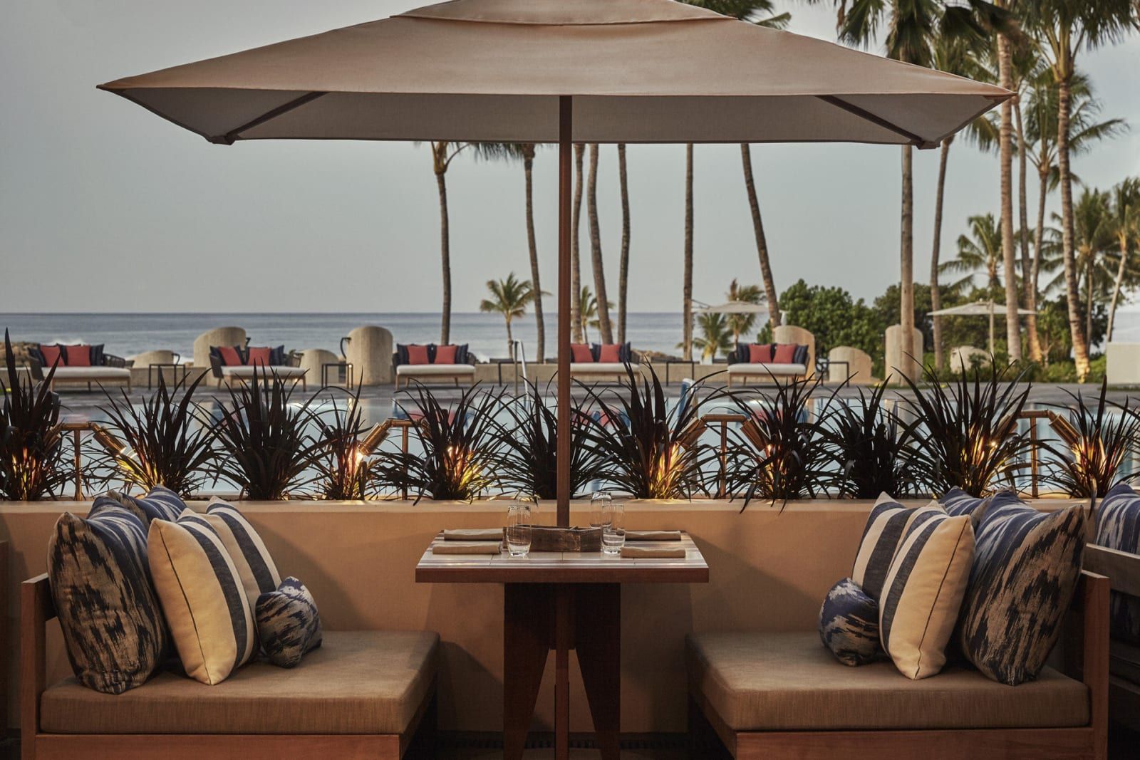 Cushioned outdoor seating under an umbrella at La Hiki