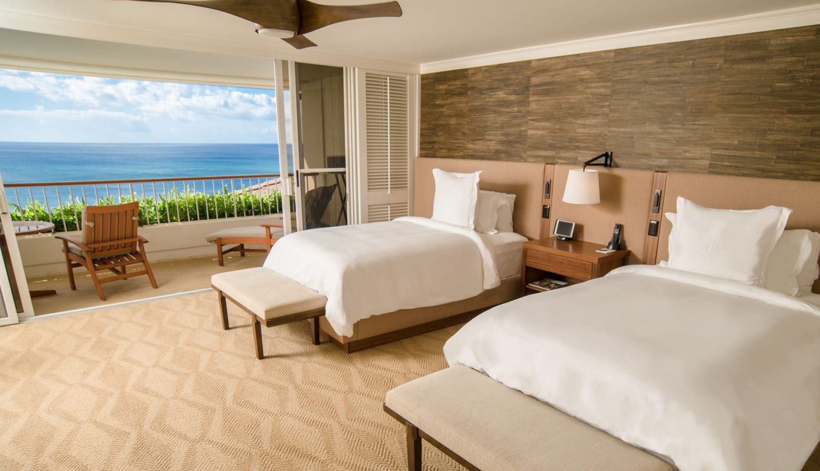 An oceanfront room with two beds and a wide view of the water
