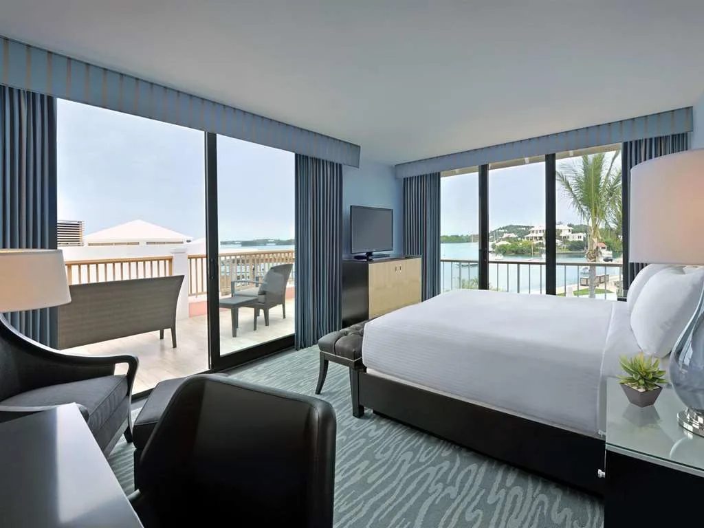 A guest room with floor-to-ceiling windows and a balcony over the harbor