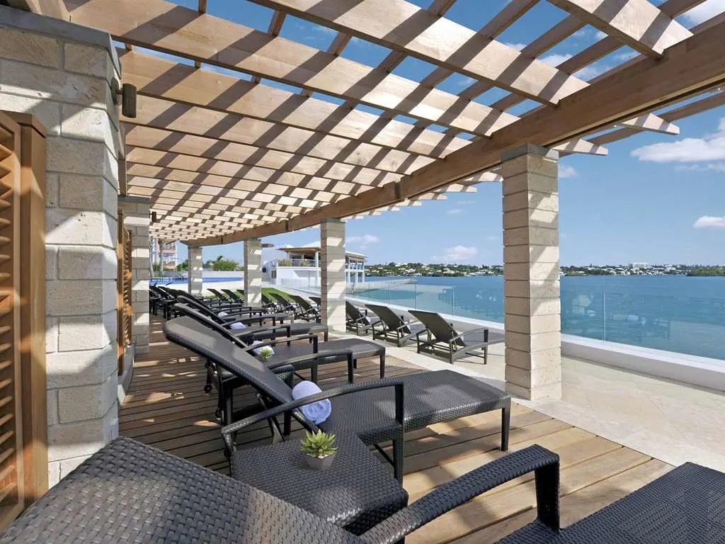 Loungers beneath a stone pergola beside the pool, looking out to the harbor