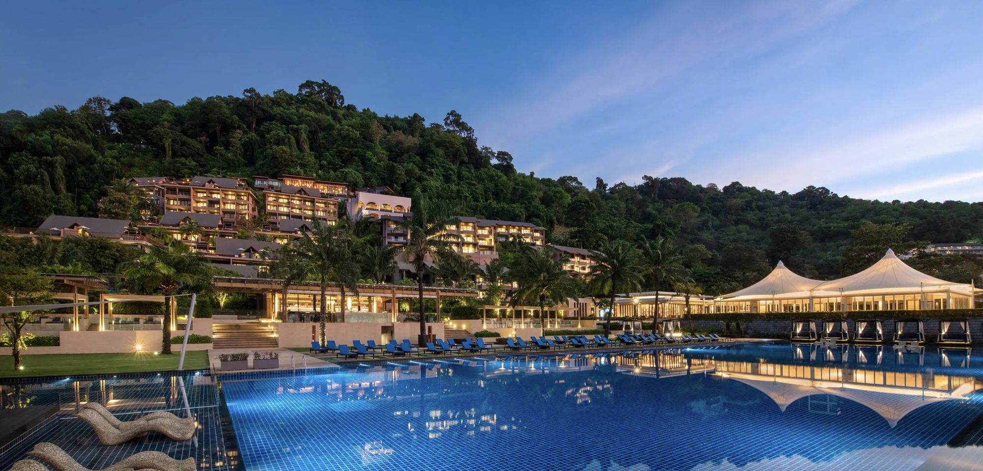 The main pool glowing at dusk below the hillside resort