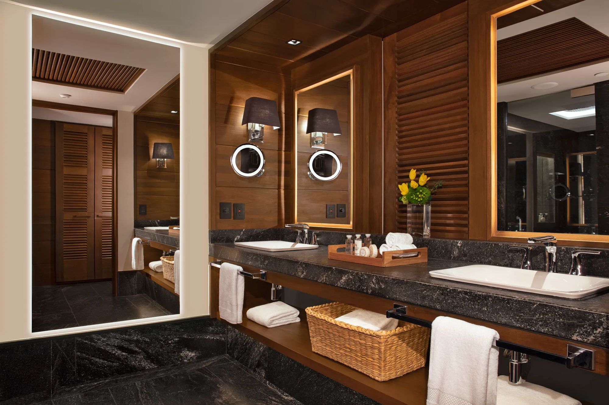 A Signature Suite bath in dark marble and warm wood