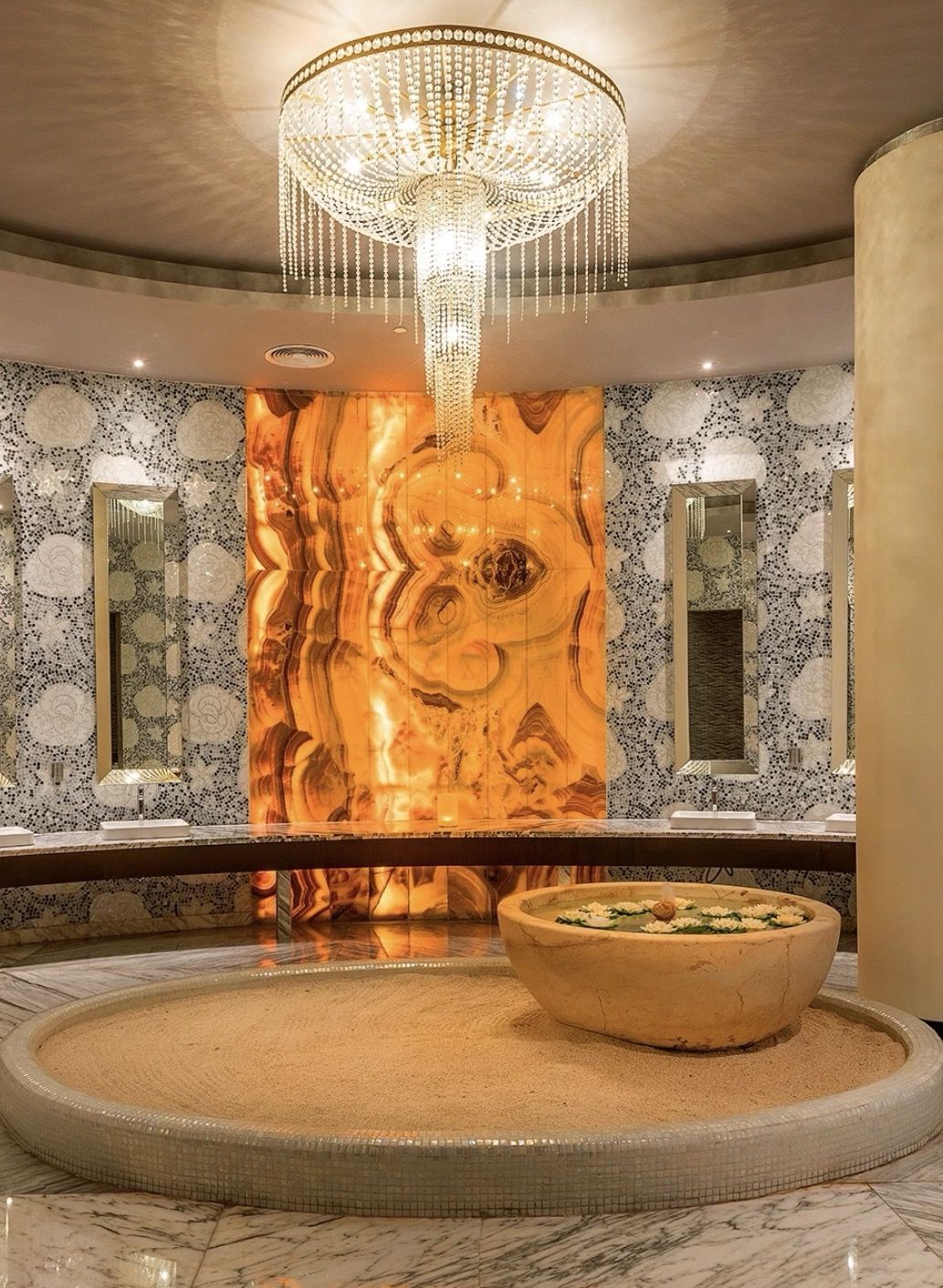 The spa's glowing onyx wall beneath a crystal chandelier