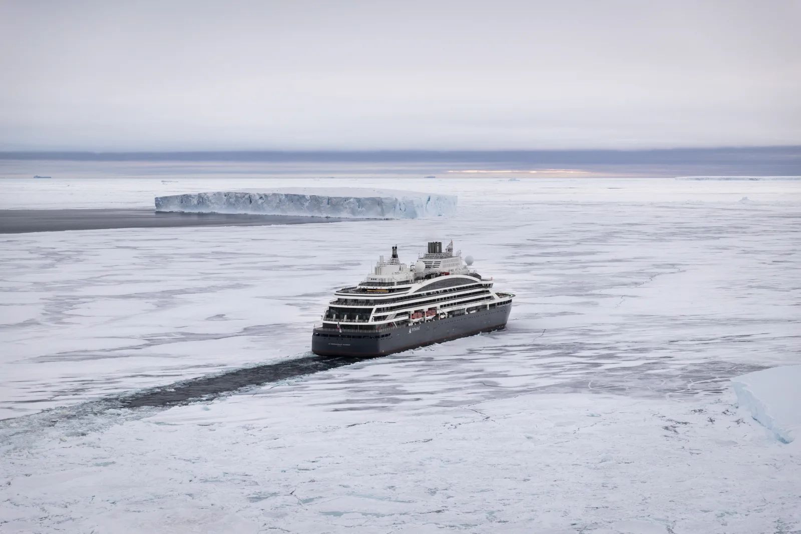 An expedition ship leaving a path through white pack ice