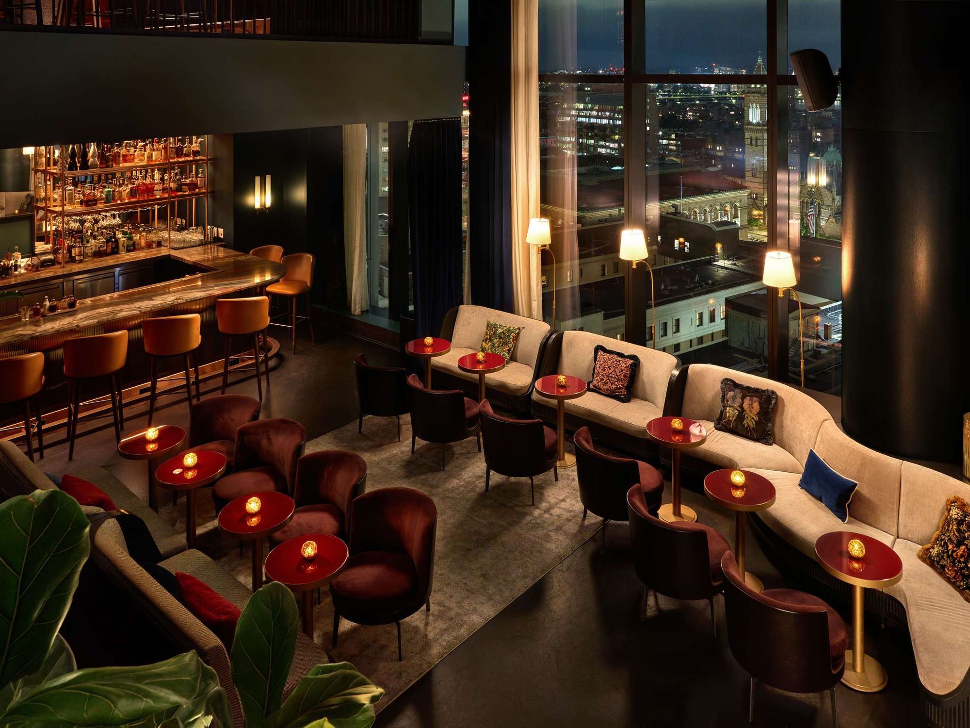 An evening restaurant with red chairs and a glowing bar