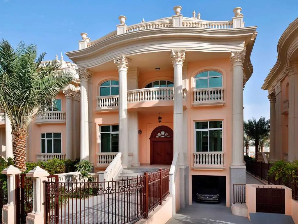 A columned villa with balconies, set among palms