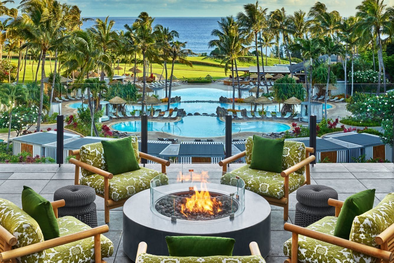 A fire pit ringed by armchairs, overlooking the pools and the sea