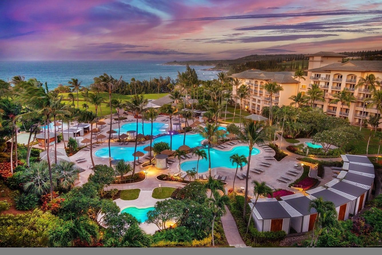 The resort's tiered pools and gardens at sunset, with the ocean beyond