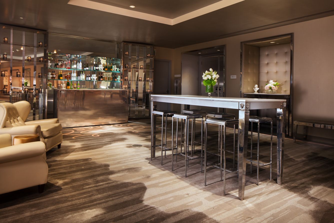 A bar and lounge with tall stools and a mirrored back wall
