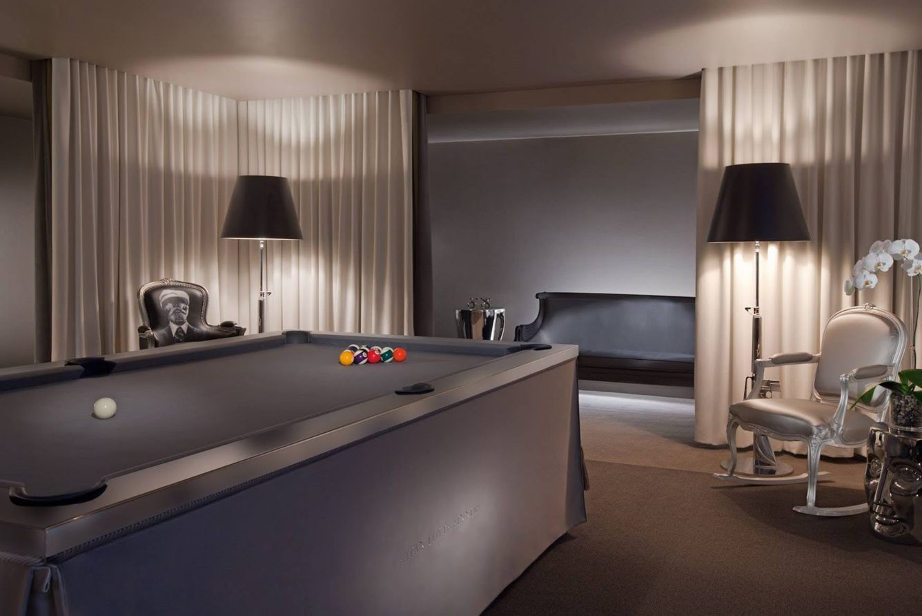 A billiards table in a dim, curtained room